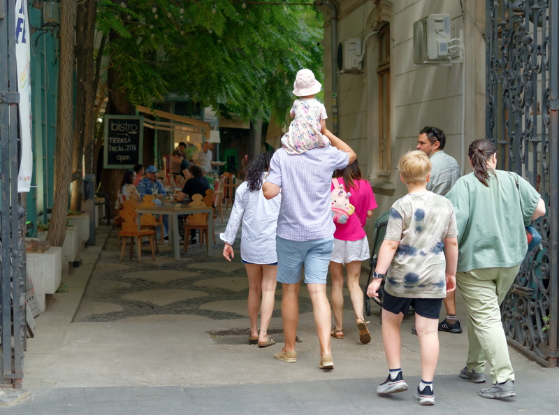 A group of people walking along a cobblestone street toward a bistro called La Ingineri Bistro in Bucharest